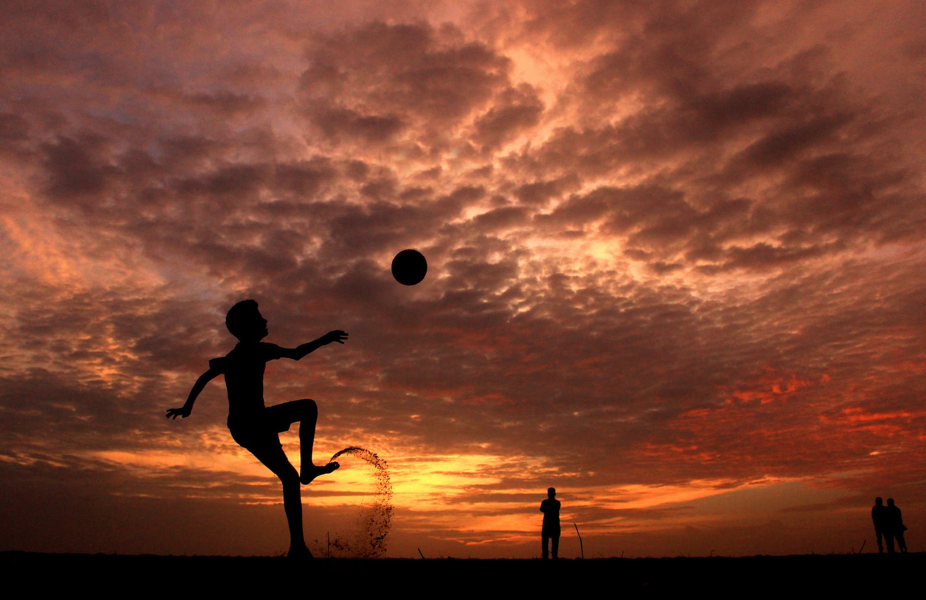 silhouette of a boy playing ball during sunset