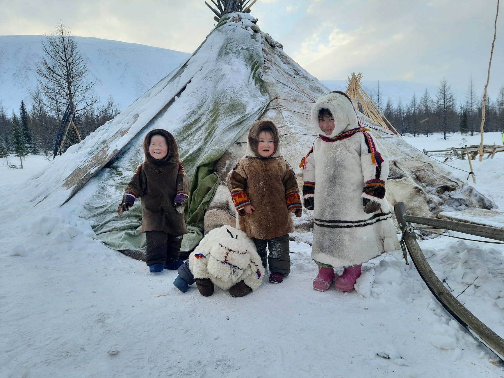 a group of children wearing parkas beside a tupik